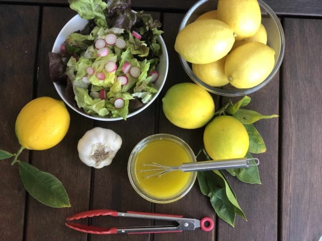 romain lettuce with sliced radishes and whole bright yellow lemons on table for salad