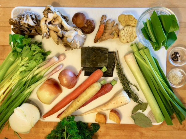 fresh celery, mushrooms, carrots, seaweed, and onions on cutting board for soup