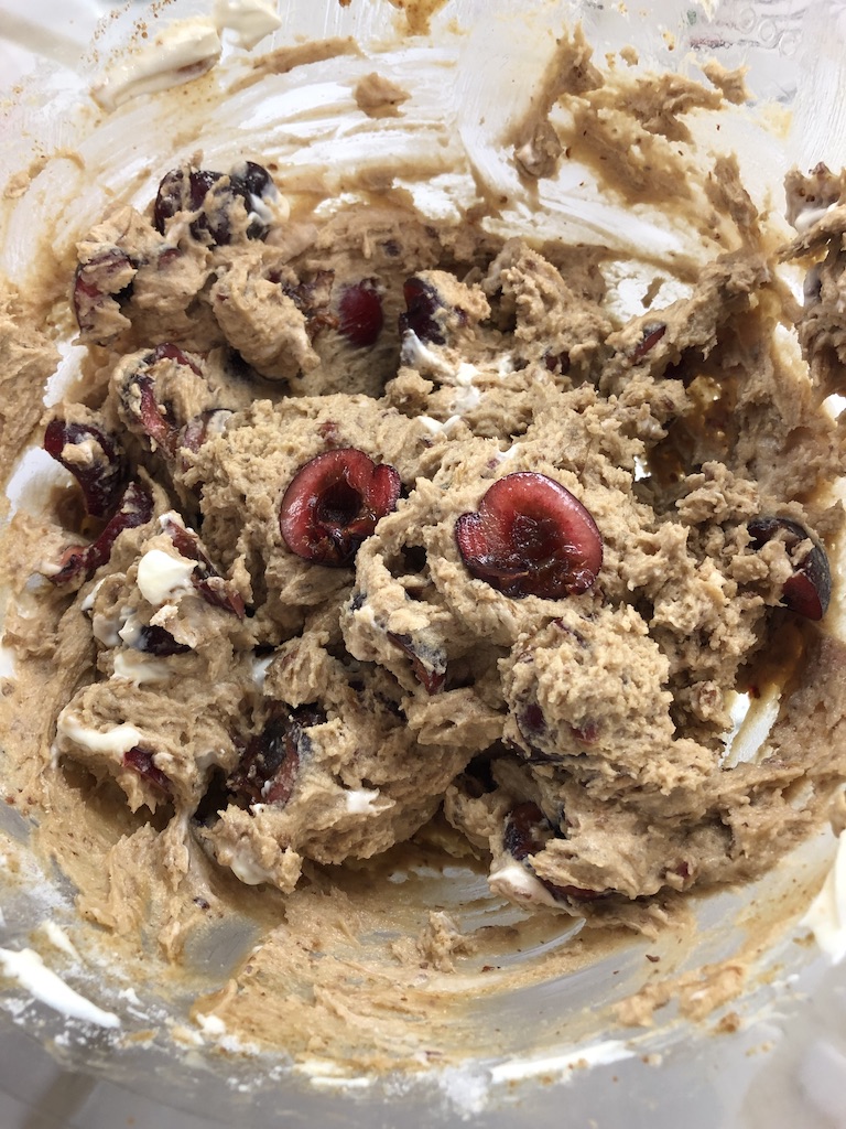 cherry muffin batter with sliced cherries in clear bowl