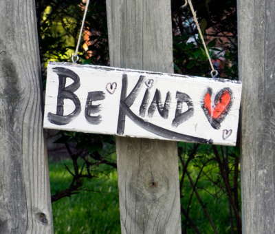 Be Kind sign on a wood fence